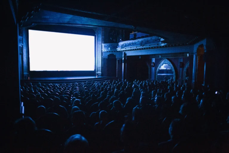 A full cinema theater audience watching a movie on the big screen at night