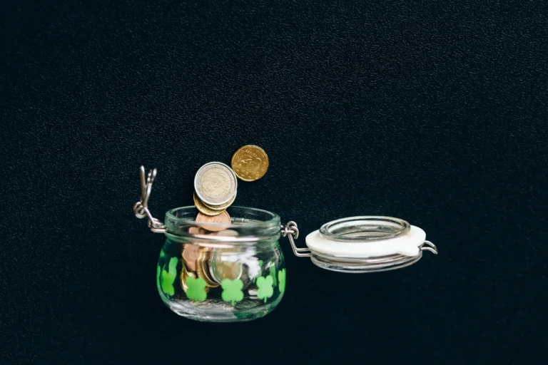 Coins falling into a glass jar representing 401k and IRA retirement contribution limits