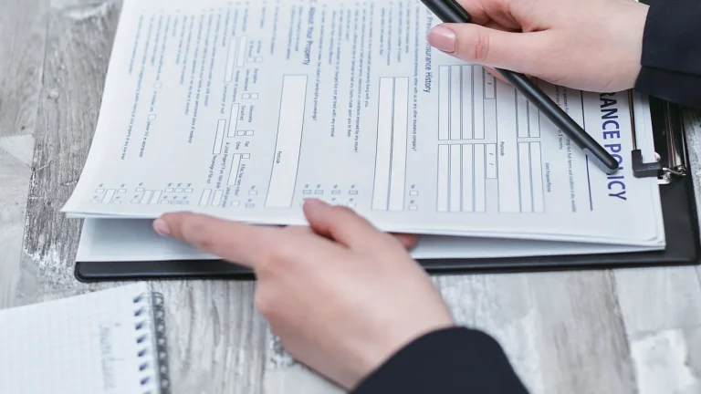 Hands reviewing health insurance paperwork on a table with a pen