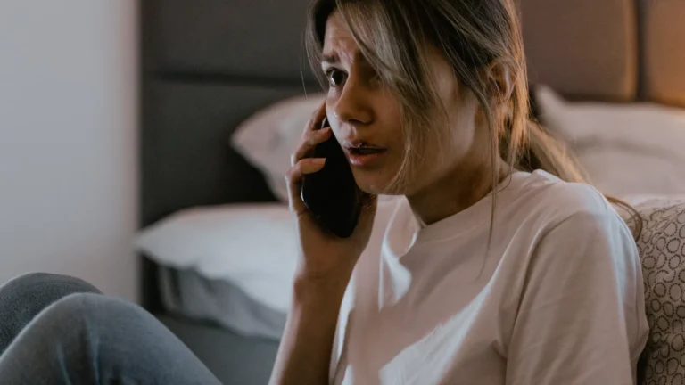 Worried woman holding a phone to her ear during a distressing call, illustrating an AI voice cloning scam