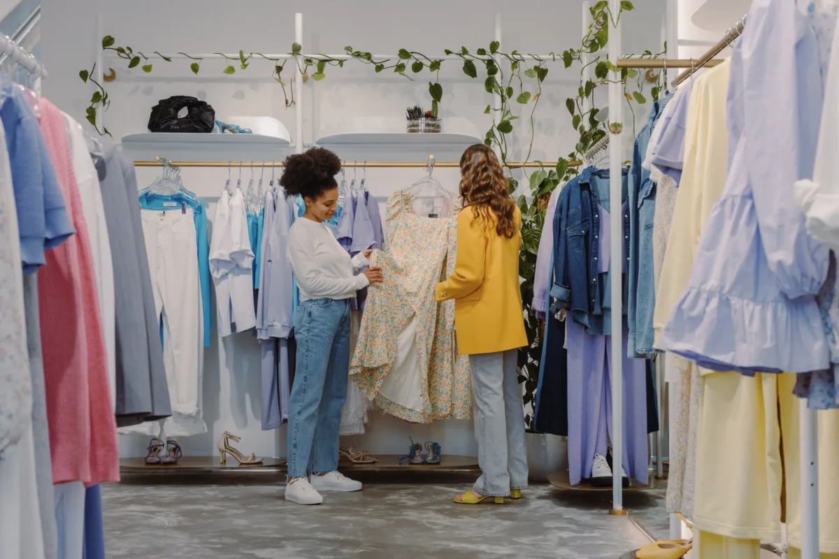 Two shoppers browsing racks of clothing in a fast-fashion boutique