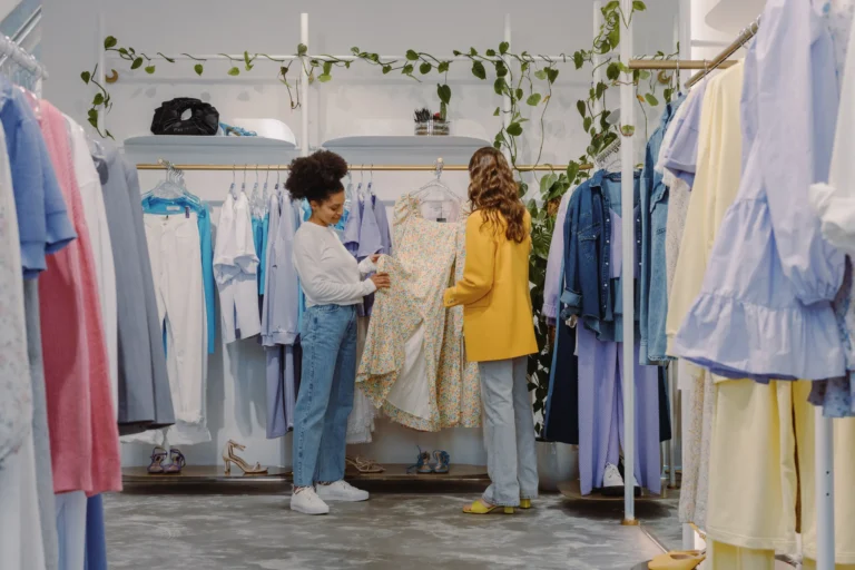 Two shoppers browsing racks of clothing in a fast-fashion boutique