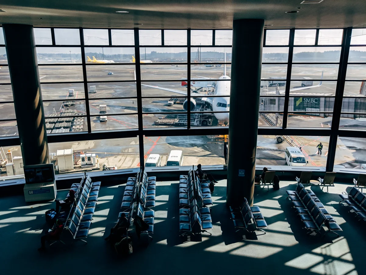 Traveler looking out an airport terminal window at a parked airplane during a flight delay