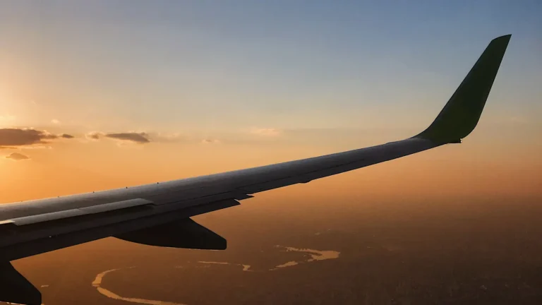 Airplane wing in flight against a sunset sky