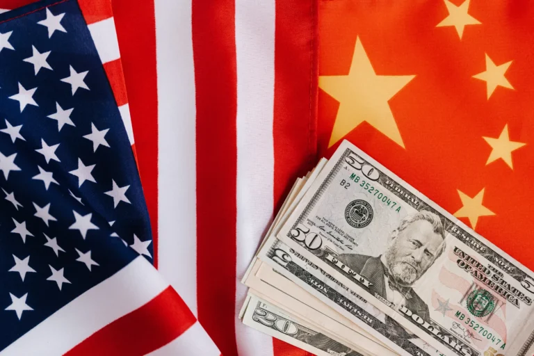 American and Chinese flags displayed with US dollar bills, symbolizing US-China trade relations