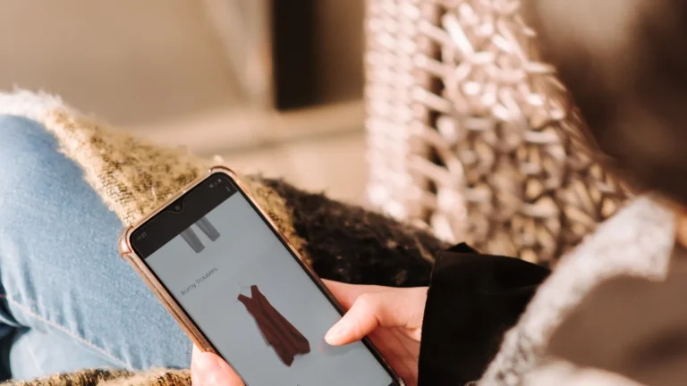 Woman sitting in an armchair browsing clothes on her smartphone