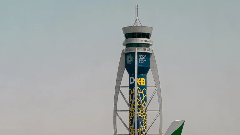 Emirates airplane on the tarmac at Dubai International Airport beside the control tower