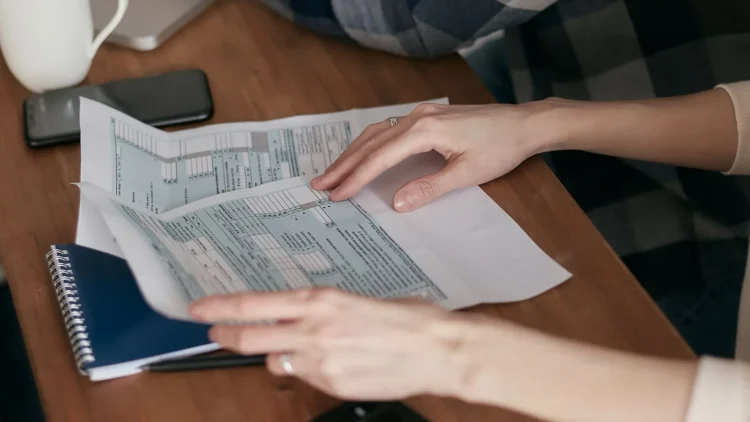 Person holding tax forms at a wooden table