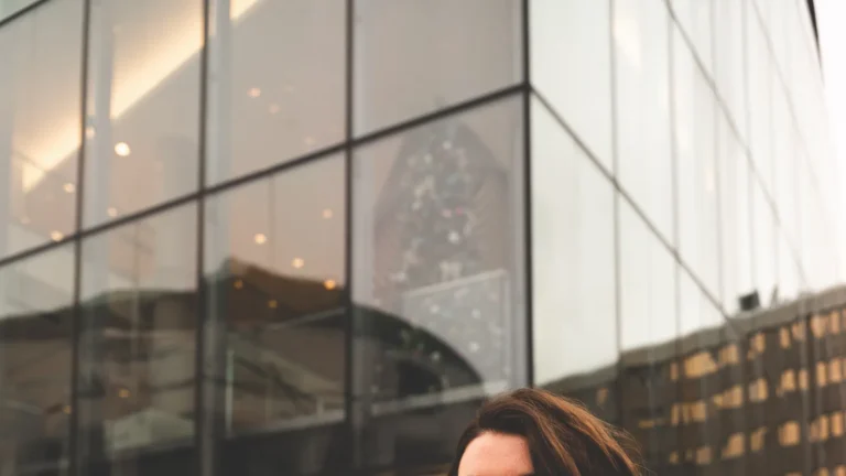 Woman in a puffer jacket and scarf standing in a snowy city