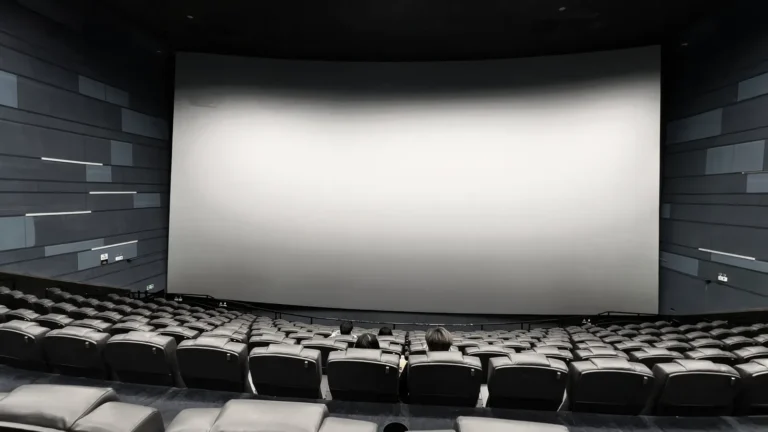 Empty movie theater seats facing a large screen