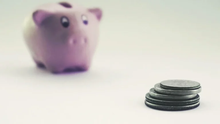Stack of coins beside a piggy bank representing savings