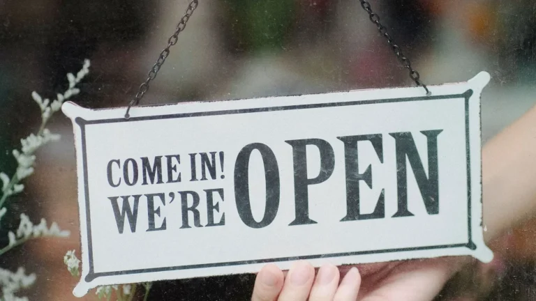 Shop owner turning an open sign on a glass storefront door