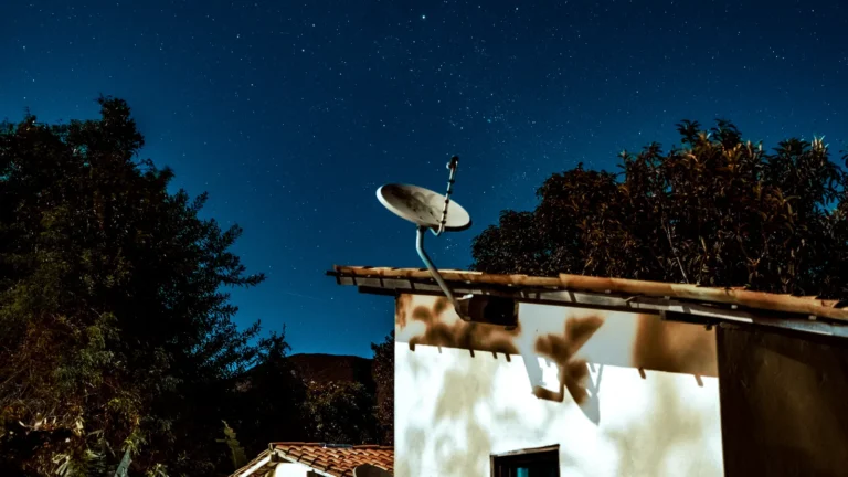 Satellite internet dish on a rural house under a starry night sky