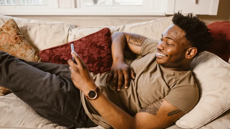 Man relaxing on a couch watching a video on his smartphone